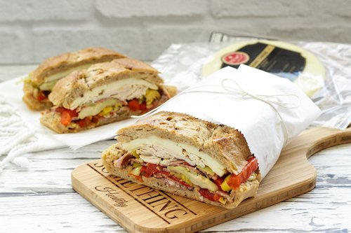 Italian PIcnic Sandwich wrapped in white paper on a cutting board