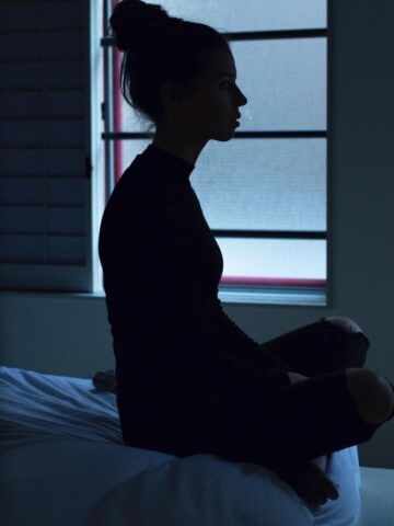 a silhouette of a woman sitting in bed