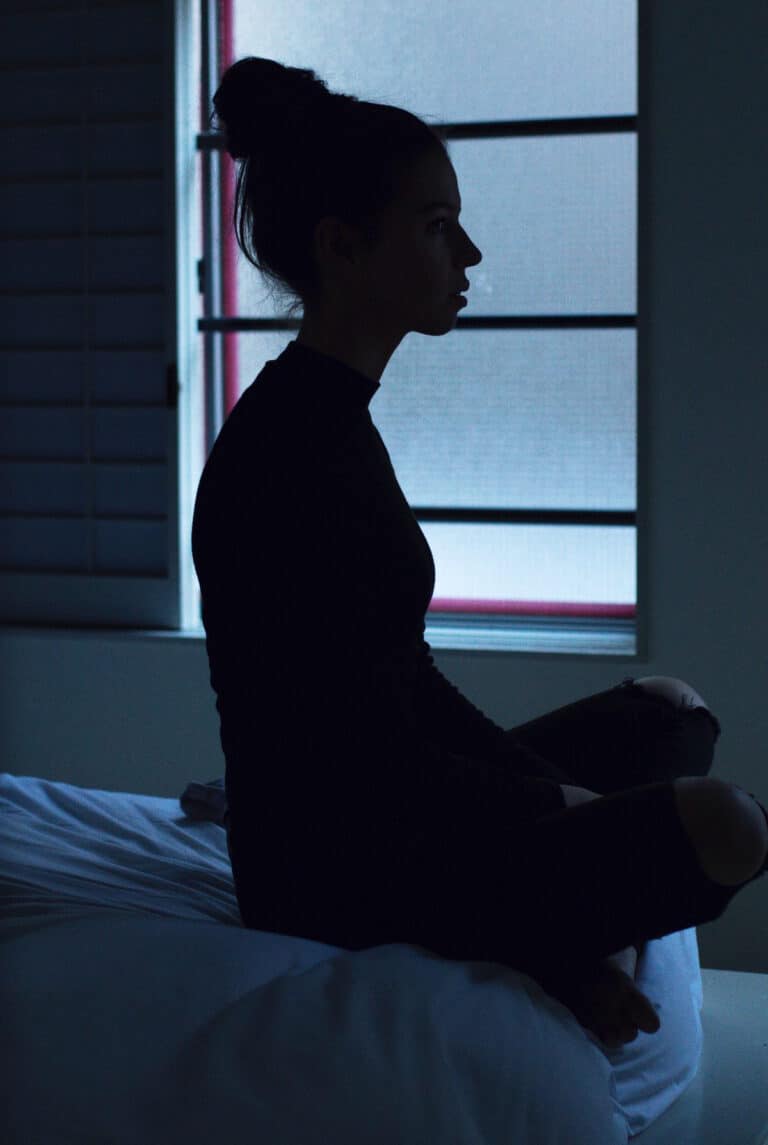 a silhouette of a woman sitting in bed