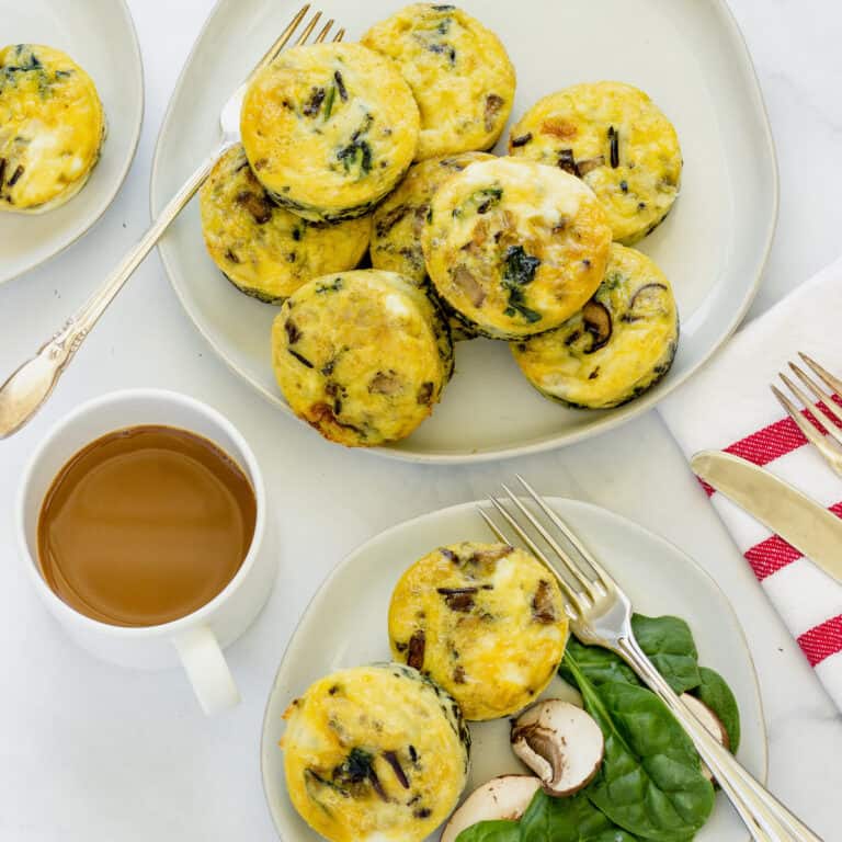 A platter of egg muffin cups next to a cup of coffee and a smaller plate of 2 egg muffins