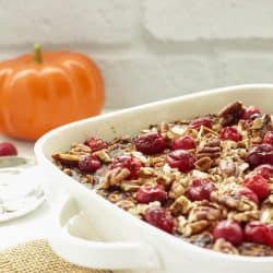 White casserole dish with pumpkin gingerbread baked oatmeal and a pumpkin in the background