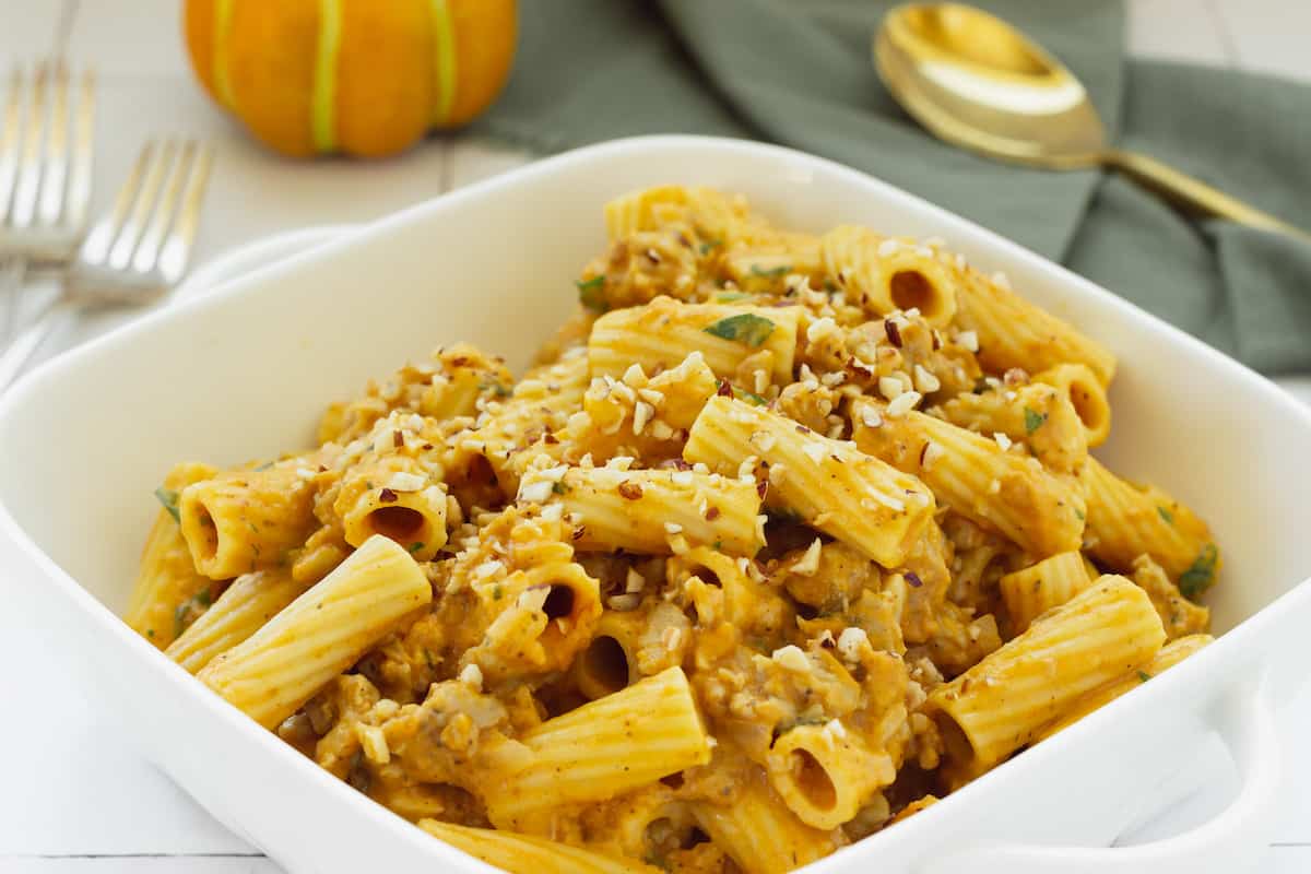 A white casserole dish filled with creamy pumpkin pasta sauce.