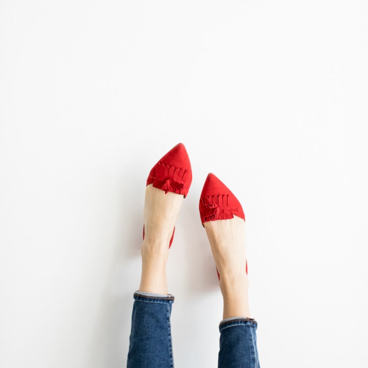 a woman's feet with red shoes and jeans.